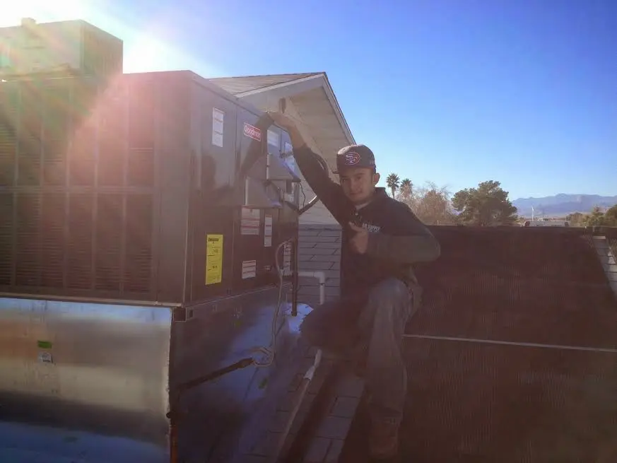 HVAC technician performing Air Duct Repair on a rooftop unit in Otis Orchards-East Farms